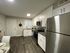 Modern kitchen with sleek stainless steel appliances, pristine white cabinetry, and elegant dark wood flooring, creating an inviting cooking space.