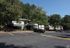 Charming garden-style apartment complex with lush greenery and ample parking under a clear blue sky.