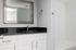 Sleek modern bathroom with elegant black countertop, large mirror, and tiled bathtub, offering a stylish and functional space.