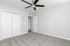 Bright and spacious bedroom featuring plush carpeting, modern ceiling fan, and ample closet space in a contemporary apartment.