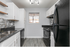 Modern kitchen with sleek black appliances, elegant gray backsplash, and ample cabinetry.