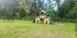Charming outdoor play area with a wooden playground structure set against a backdrop of lush greenery, perfect for family fun and relaxation.