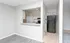 Bright and modern apartment kitchen with sleek black appliances and elegant white cabinetry, featuring a convenient pass-through breakfast bar and stylish flooring.