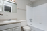 Bright and modern bathroom with elegant fixtures, featuring a sleek countertop, stylish vanity, and pristine bathtub.
