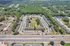 Inviting aerial view of a serene apartment complex surrounded by lush greenery, showcasing ample parking and well-maintained pathways.