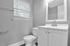 Sleek and modern bathroom with bright vanity, large mirror, and natural light offering a refreshing ambiance.