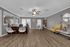 Spacious modern living area featuring elegant wood flooring, a chic yellow armchair, and a stylish dining space with natural light.