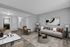 Modern apartment living room featuring a stylish gray sofa with colorful pillows, elegant armchairs, and sleek marble dining table. Warm ambient lighting and abstract art enhance the sophisticated decor.