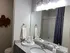 Elegant bathroom featuring a sleek granite countertop, large mirror, and stylish lighting, exuding modern sophistication.