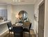 Elegant dining area with a cozy round table, stylish chairs, and a large decorative mirror, creating a welcoming ambiance.