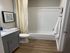 Elegant bathroom with modern fixtures, featuring a sleek vanity, pristine bathtub, and contemporary lighting accents.
