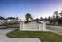 Inviting entrance to Odyssey at Laurel Island apartment homes, set against a serene sunset backdrop with lush landscaping and modern architecture.