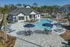 Luxurious apartment complex featuring a sparkling outdoor pool, stylish lounge chairs, and chic umbrellas, framed by lush greenery and modern architecture.