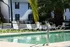 Inviting outdoor pool area with sun loungers and lush palm trees, perfect for relaxation and soaking up the sun.