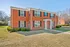 Charming brick apartment building with classic windows and well-kept lawn, nestled in a serene residential area.