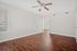 Bright and inviting living space with elegant hardwood flooring, large windows, and a ceiling fan for comfort.