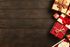 Elegantly wrapped gifts with rustic and festive ribbons on a rich wooden surface, creating a warm holiday ambiance.
