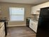 Modern apartment kitchen with sleek black appliances, elegant white cabinetry, and chic granite countertops offering a stylish cooking space.