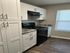 Modern kitchen with sleek white cabinetry, dark countertops, and an elegant black stove, perfect for culinary enthusiasts.