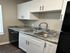 Modern kitchen featuring sleek dual-basin sink, elegant granite countertops, and pristine white cabinetry with chic handles.