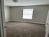 Bright and cozy bedroom featuring plush carpet, a large window for natural light, and neutral-toned walls, perfect for a peaceful retreat.