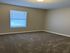 Cozy bedroom with fresh carpet, neutral walls, and natural light through a window with blinds.