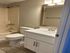 Modern bathroom featuring a sleek vanity with ample storage, pristine fixtures, and a full shower-tub combo.