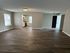 Inviting open-concept living area with sleek hardwood floors leading to a modern kitchen and bright natural light.