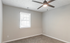 Bright and airy bedroom with modern ceiling fan, plush carpet, and natural light from large window.