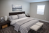 Elegant bedroom with a plush gray quilted bedspread, modern furniture, and soothing artwork, designed for ultimate comfort and style.
