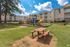 Inviting apartment community with bright playground, surrounded by lush greenery and spacious residential buildings for relaxed living.