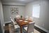Elegant dining room with a sleek wooden table set for six, featuring modern beige chairs and tasteful wall art, perfect for stylish entertaining.