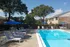 Inviting apartment complex pool area with comfortable lounge chairs, vibrant blue umbrellas, and lush greenery, perfect for relaxation.