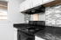 Modern kitchen with sleek black countertops, electric stove, and stylish grey tile backsplash.