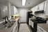 Charming kitchen with modern white cabinets, sleek countertops, and cozy decor, featuring a black oven and fridge.