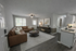 Inviting open-concept living space featuring a plush leather sectional, chic decor, and modern kitchenette.