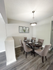 Elegant dining area with a modern chandelier, showcasing a stylish round table surrounded by plush, tufted chairs on sleek wooden flooring.