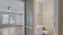 Bright and inviting room with modern ceiling fan and large window, adjacent to a cozy, well-lit bathroom with classic fixtures.