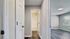 Bright hallway leading to a modern bathroom and a spacious room with large windows, featuring sleek hardwood floors.