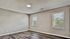 Bright and spacious empty room with modern laminate flooring and two large windows offering natural sunlight.