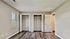 Inviting bedroom space with two open closets, sleek hardwood flooring, and natural light streaming through a window.