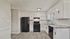 Modern kitchen with sleek black appliances, elegant white cabinets, and stylish wood flooring.