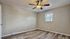Inviting bedroom with modern ceiling fan, neutral walls, and elegant wood-style flooring.