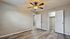 Bright and airy bedroom with modern ceiling fan, elegant wood flooring, and a spacious walk-in closet.