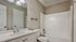 Pristine bathroom featuring a modern sink, elegant lighting, and a spacious tub with white finishes.