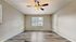 Bright and spacious room with elegant wood flooring, modern ceiling fan, and large window inviting natural light.