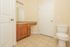 Bright and welcoming bathroom featuring elegant granite countertops, stylish wooden cabinetry, and pristine tile flooring.