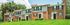 Charming brick townhomes with classic black shutters, nestled in a lush green neighborhood, under clear blue skies.