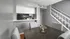Chic dining area with a modern open kitchen, featuring sleek grey walls and a stylish staircase.