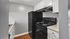 Chic and modern kitchen with sleek black appliances, bright white cabinetry, and elegant wood flooring.